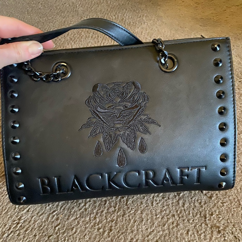 Blackcraft purse black has 3 compartment and 2 closers sides are red color